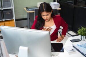 Tired woman clutching her chest and feeling lightheaded, symbolizing a potential episode of syncope or fainting
