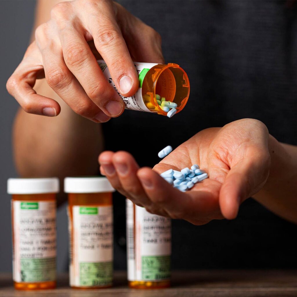 Person pouring pills from a prescription bottle, illustrating how drug ads can hide real harm even when benefit is small