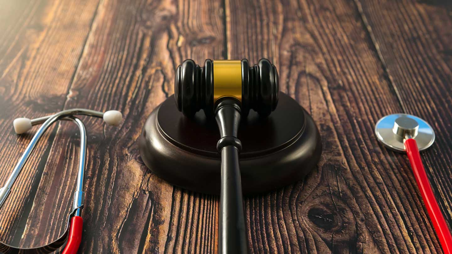 Gavel on a desk with stethoscope, illustrating a state medical board investigation and guideline enforcement in medicine