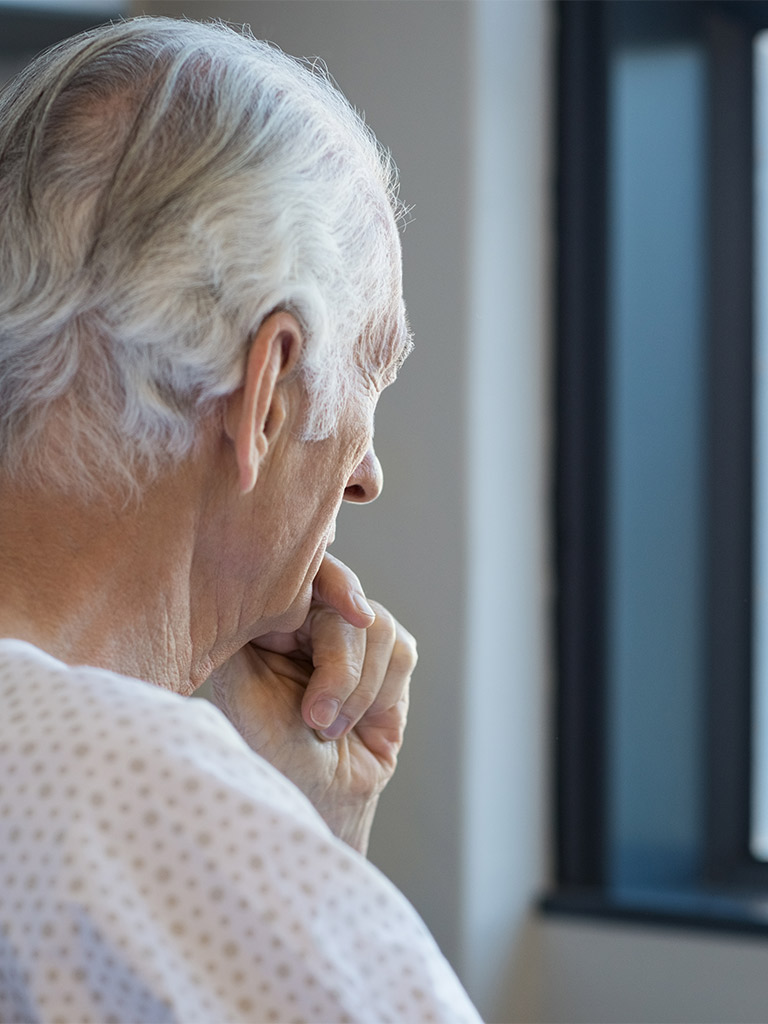 Thoughtful older patient looking out a window, illustrating anxiety from “too much information” in amyloid testing for Alzheimer’s