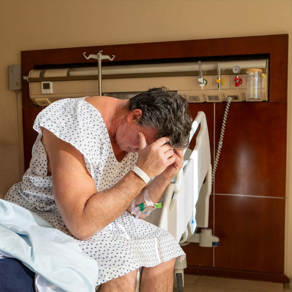 Upset patient sitting on a hospital bed, illustrating how a troponin test without chest pain can trigger emergency room overtreatment