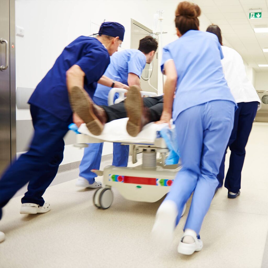 Hospital staff rushing a patient on a gurney down a corridor, illustrating why the ER can feel dangerous and lead to emergency room overtreatment
